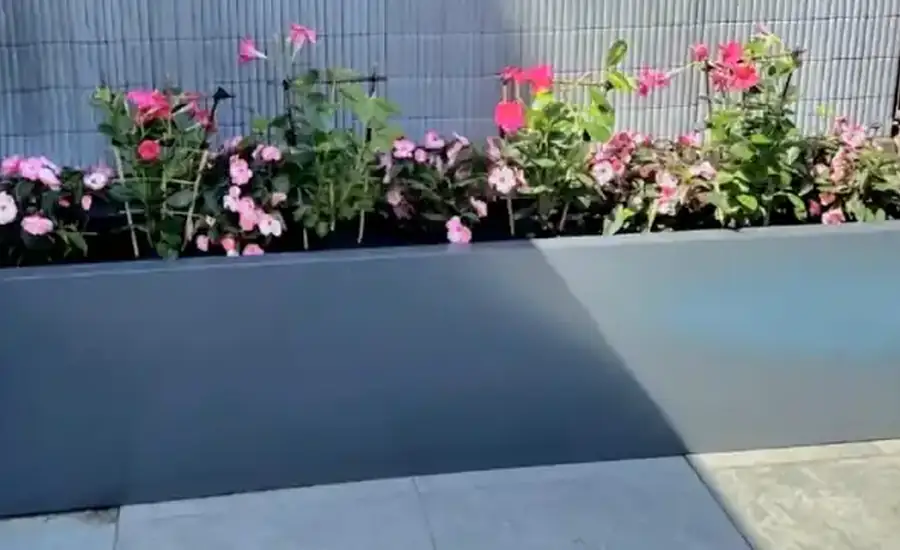 Aangeleverde praktijkfoto van een antracietkleurige stalen plantenbak in een tuin